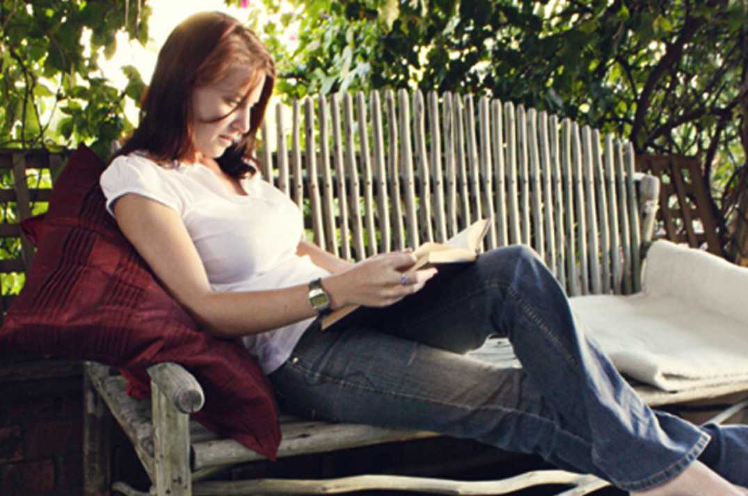 Woman lounging on a Pole Yard wooden garden bench